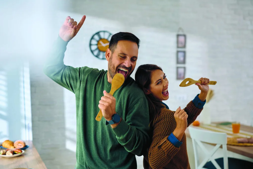 Carefree couple having fun and singing in kitchen.