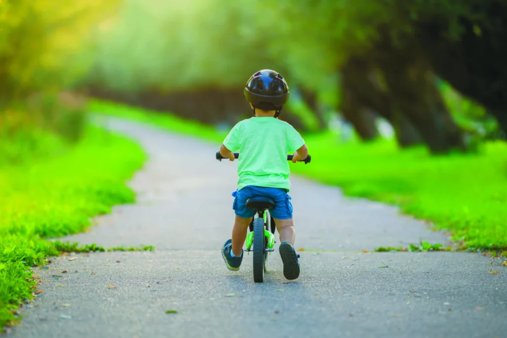 Little boy with helmet running and riding on first bike without