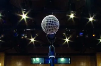 A microphone on a lit stage at Cranleigh Arts Centre, looking out over rows of empty seats