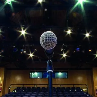 A microphone on a lit stage at Cranleigh Arts Centre, looking out over rows of empty seats