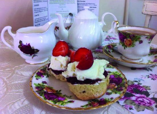 A cream tea with scones, clotted cream, strawberries and a pot of tea