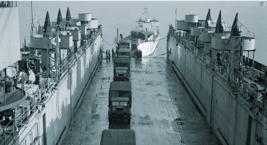 HMS Eastway taking troop vehicles aboard its rear deck in 1943