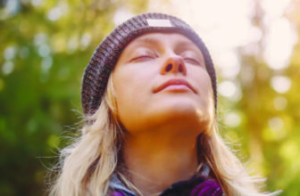 A woman breathing calmly through her nose, face turned up to the light