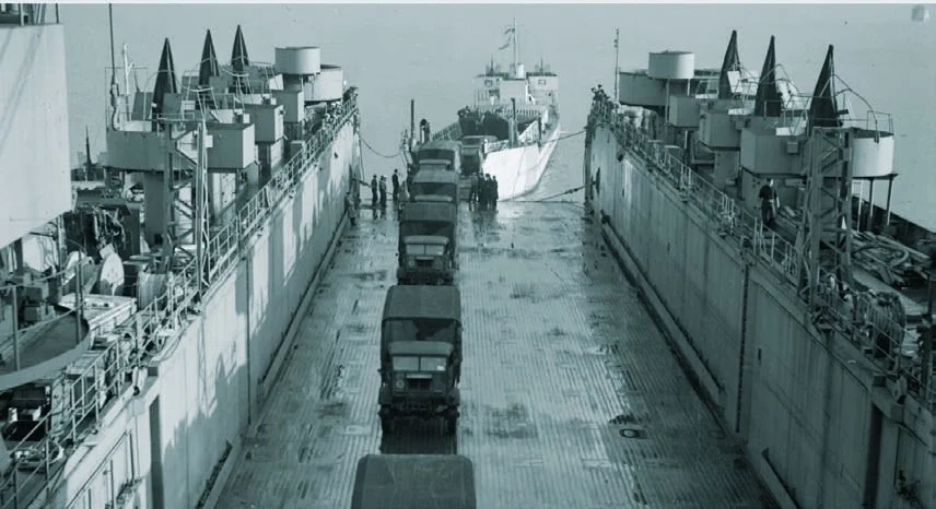 HMS Eastway taking troop vehicles aboard its rear deck in 1943