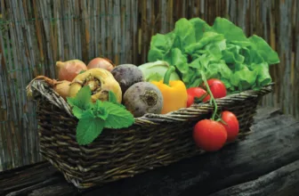 A wicker basket of fresh vegetables including tomatoes, peppers, beetroot and lettuce