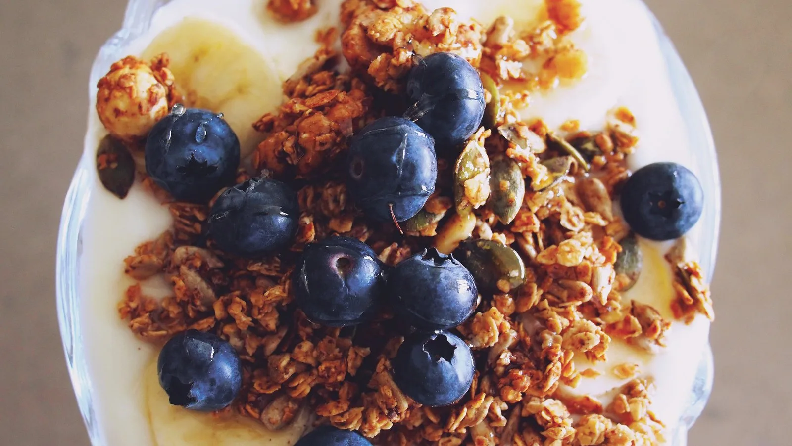 A breakfast bowl of granola topped with blueberries, banana and seeds