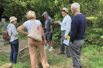 Visitors on a guided tour of the graveyard, among trees and headstones