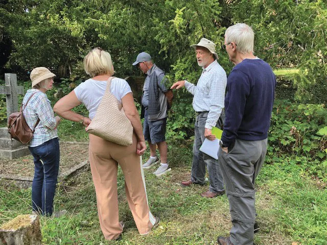 Visitors on a guided tour of the graveyard, among trees and headstones